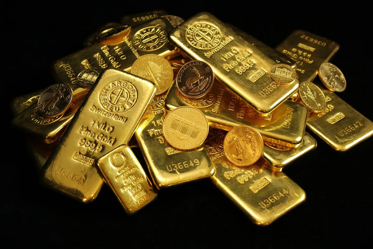 A collection of shiny gold bars and coins representing wealth and investment in precious metals.